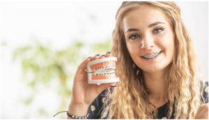 Smiling girl with braces holding jaw with braces Orthodontist in 12309